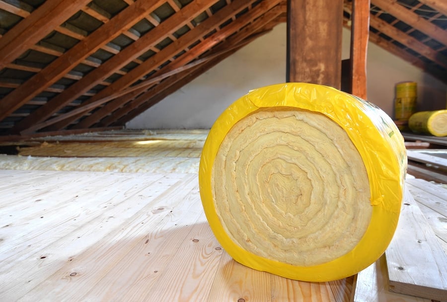 A roll of insulating glass wool on an attic floor