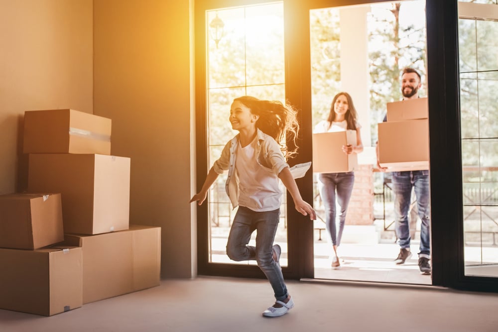 Happy smiling family with one child standing in new home on moving day.